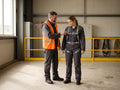An instructor checking the fit of a full body safety harness on a learner at ground level